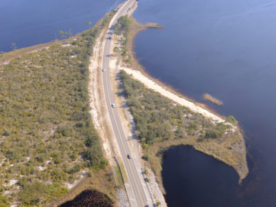 Vehicles cruise along Scenic Highway 30-A near one of Walton County's 15 named coastal dune lakes. These lakes are an unusual geographical feature and are only found in a few places in the world. The only other places on Earth to find a coastal dune lake are in Madagascar, Australia, New Zealand and Oregon. | Photo by: Andrew Wardlow