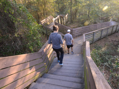 Visitors walk down the boardwalk at Bay Bluffs Park along Pensacola Scenic Bluffs Highway. The city-owned, 32-acre Bay Bluffs Park features the extensive boardwalk that leads visitors through thick forest to the base of the giant cliffs and the waters of Escambia Bay. Tall bluffs of red clay line the beaches, which offer a magnificent spot to watch the sun rise over the bay.