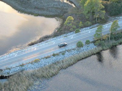 Vehicles cruise along Scenic Highway 30A past one of Walton County's 15 named coastal dune lakes. These lakes are an unusual geographical feature and are only found in a few places in the world.The only other places on Earth to find a coastal dune lake are in Madagascar, Australia, New Zealand and Oregon. | Photo by: Andrew Wardlow